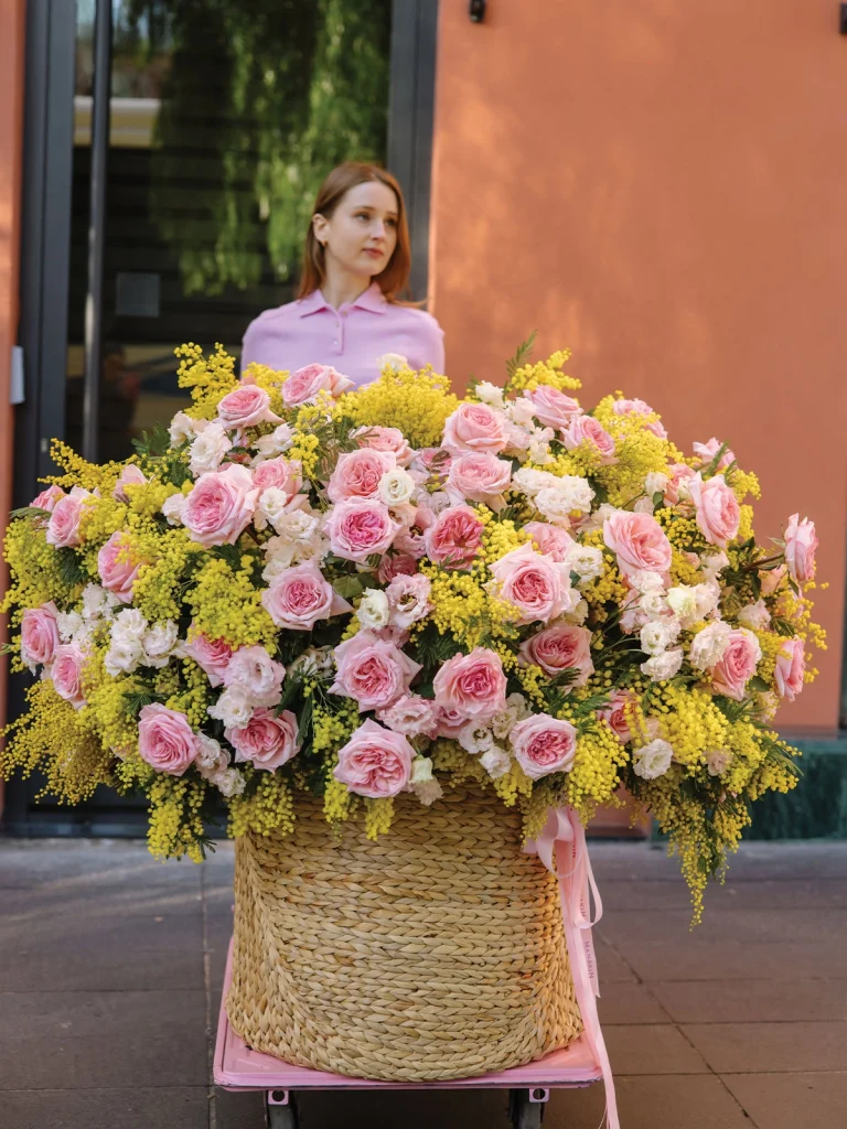 Spring Symphony arrangement positioned at the entrance of a classical building with elegant arched doorway, displaying massive floral dome against period architecture
