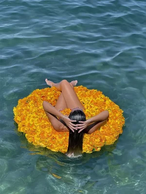 Woman relaxing on a floating bed of yellow gerbera daisy flower arrangement