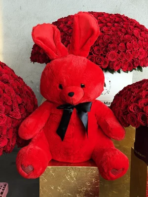 Full view of 70cm red plush bunny with black satin bow sitting on gold pedestal with luxury red rose boxes from Manakin Fleurs, Valentine's Day gift Nice