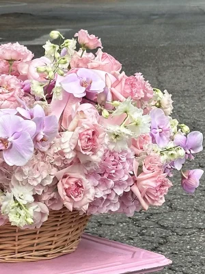 Close-up of blush pink roses and lilac orchids in a woven basket delivered in Monaco